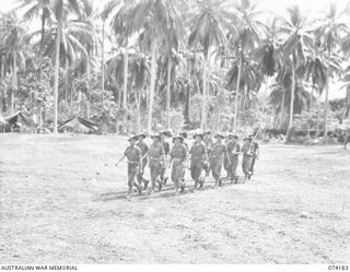 PERSONNEL OF NO. 1 PLATOON, HEADQUARTERS COMPANY, 57/60TH INFANTRY BATTALION MOVING ACROSS THE UNIT PARADE GROUND AT THE CONCLUSION OF THE MORNING PARADE. IDENTIFIED PERSONNEL ARE:- VX5209 ..