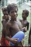 Boys, one smiles and holds blue balloon