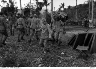 KAIRIRU ISLAND, NEW GUINEA. 1945-09-17. AMONGST THE 700 JAPANESE NAVAL PERSONNEL TRANSFERRED TO MUSCHU ISLAND WERE MANY SICK; SHOWN IS ONE CASE HOBBLING DOWN TO THE BARGE. FOLLOWING THE SURRENDER ..