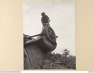 WEWAK AREA, NEW GUINEA. 1945-10-13. PRIVATE W. MUMFORD, 3 MOBILE TYRE WORKSHOP SECTION KNOCKING THE WHEEL FROM A JAPANESE TRUCK TO REMOVE TYRE