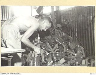 17 MILE, PORT MORESBY AREA, NEW GUINEA. 1943-12-13. VX80542 PRIVATE S. P. CULLEN, STOREMAN OF THE RETURNED STORES SECTION, 10TH AUSTRALIAN ADVANCED ORDNANCE DEPOT WITH A PILE OF ANTI-GAS ..