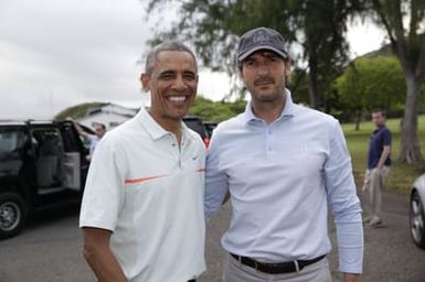 Barack Obama confers with Robert Baker after he plays golf in Kaneohe Bay, Hawaii, December 24, 2014