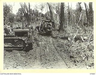 BOUGAINVILLE ISLAND. 1945-02-12. TROOPS OF THE 5TH FIELD COMPANY, USING A BULLDOZER AND TRACTOR TO REPAIR A SECTION OF THE MOSIGETTA ROAD WHICH WAS DESTROYED BY THE ROYAL NEW ZEALAND AIR FORCE WHEN ..