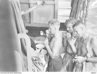 AT SEA. 1945-03-31. SERGEANT H. POTTER, (1), WITH DRIVER BRYANT, (2), AND SERGEANT A. MCDONALD, (3), GETTING THEIR SHARE OF TURKEY ON THE TOP DECK ABOARD THE VAN HEUTSZ. THE MEN, MEMBERS OF THE ..