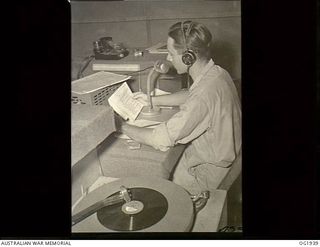 MADANG, NEW GUINEA. C. 1944-10. 435397 SERGEANT F. E. SHEPPARD, BRISBANE, QLD, AT THE CONTROL DESK MICROPHONE OF RAAF RADIO "THE VOICE OF THE ISLANDS". HE WAS FORMERLY ANNOUNCER AND REGIONAL ..