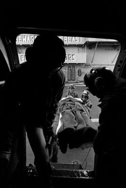 A view looking out from a CH-46 Sea Knight helicopter as a wounded Marine is carried aboard for medevac from the amphibious assault ship USS GUAM (LPH-9), during operations off the coast of Beirut, Lebanon