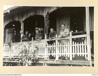 ALEXISHAFEN, NEW GUINEA. 1944-05. OFFICERS OF THE 2/15TH FIELD AMBULANCE GROUPED BESIDE A NATIVE CARVING ON THE VERANDAH OF THEIR QUARTERS AT THE OLD CATHOLIC MISSION. IDENTIFIED PERSONNEL ARE:- ..