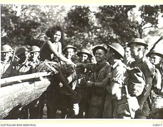 PAPUA, NEW GUINEA. 1942-07. MEMBERS OF AN AUSTRALIAN INFANTRY PATROL STOP IN A COASTAL VILLAGE TO MAKE THE ACQUAINTANCE OF A DUSKY "KIKINI" WHICH IS THE PAPUAN TRANSLATION OF A YOUNG GIRL