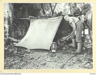 FINSCHHAFEN AREA, NEW GUINEA, 1944-04-23. VX1330 SERGEANT B. SEALES, WITHIN HEADQUARTERS FINSCHHAFEN BASE SUB-AREA, OUTSIDE THE ONE MAN DWELLING HE HAD BUILT TO WITHSTAND ALL WEATHERS