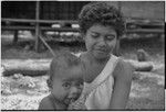 Baby, looking at camera, sits on young woman's lap