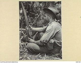 DAGUA, NEW GUINEA. 1945-03-27. PTE R.S. SHEEHAN, 2/2 INFANTRY BATTALION, GUARDS THE FLANK OF A FORWARD POSITION OF A COMPANY AS IT ATTACKS JAPANESE POSITIONS