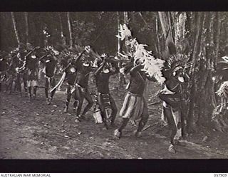 DOBODURA, NEW GUINEA. 1943-10-10. NATIVE CEREMONIAL DANCES IN PROGRESS IN THE VILLAGE CLEARING WERE ATTENDED BY ALLIED TROOPS AND NURSES