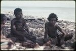 Woman and children sit on a beach near Kaibola village