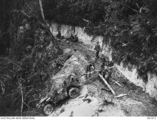 PALANKO, NEW GUINEA. 1943-12. TROOPS OF THE 26TH AUSTRALIAN INFANTRY BRIGADE RIGGING UP A FRAMEWORK SO THAT THEY CAN HAUL A CRASHED JEEP BACK ON TO THE ROAD