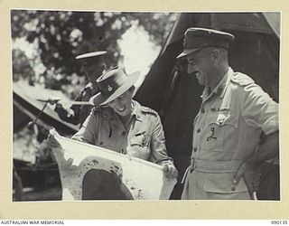 BOUGAINVILLE. 1945-03-31. LADY WAKEHURST (1), AND BRIGADIER J.R. STEVENSON, COMMANDER 11 INFANTRY BRIGADE (2), EXAMINING A JAPANESE FLAG CAPTURED IN NORTH BOUGAINVILLE. LADY WAKEHURST, LORD ..