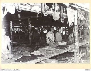 FAURO ISLAND, BOUGAINVILLE AREA. 1945-11-11. JAPANESE SOLDIERS KNEELING ON THEIR SLEEPING MATS IN A LIVING HUT IN AREA NO. 7. THEY WERE PHOTOGRAPHED DURING A TOUR OF INSPECTION OF THE JAPANESE ..