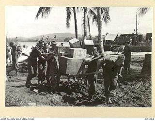 ALEXISHAFEN, NEW GUINEA. 1944-05-09. MEMBERS OF THE 4TH SUB DEPOT PLATOON, AUSTRALIAN ARMY SERVICE CORPS MADE USE OF A FORMER JAPANESE HAND CART TO PULL A CART LOADED WITH SUPPLIES FROM THE BEACH ..