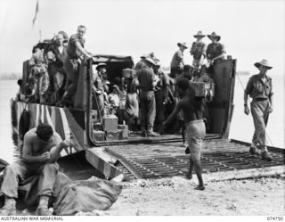 NORTH ALEXISHAFEN, NEW GUINEA. 1944. NATIVES LOADING THE COURIER BARGE OF THE 593RD UNITED STATES BARGE COMPANY FOR THE RETURN TRIP TO MADANG