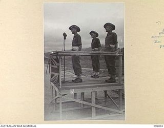 WEWAK AIRSTRIP, NEW GUINEA. 1945-09-03. BRIGADIER J.E.G. MARTIN, COMMANDER 19 INFANTRY BRIGADE (1), ON THE DAIS ADDRESSING TROOPS OF 2/4, 2/8 AND 2/11 INFANTRY BATTALIONS DURING A BRIGADE PARADE AT ..