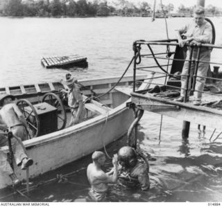 1943-05-19. NEW GUINEA. ORO BAY. ALLIED SHIP SUNK BY JAPANESE BOMBS 1943-03. JOHN E. JOHNSTONE AND CAPT. J.W. HERD, SALVAGE DIVERS, (WHO HANDLED SALVAGE OF GOLD FROM THE "NIAGARA") INSPECT SUNKEN ..