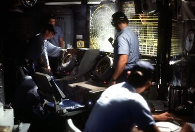 Crew members monitor radar tracking screens aboard the amphibious assault ship USS GUAM (LPH 9)