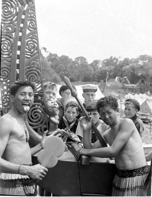 [Two Maori boys in piupiu posing beside imitation war canoe]