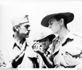 New Guinea. 1943-11. At an aerodrome film star Gary Cooper teaches an Australian soldier the finer points of doughnut eating