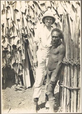 Types from villages of Evese, Ononge [Caucasian man, possibly Frank Hurley, in a safari suit with a Papuan man]