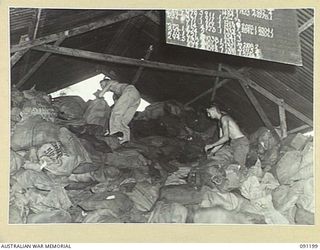 JACQUINOT BAY, NEW BRITAIN. 1945-04-26. SERGEANT R. HUGHES (1), AND PRIVATE J. HEEVEY (2), CLEARING A RECORD LOAD OF SERVICE MAIL AT 5 DIVISION AREA, 7 BASE POST OFFICE