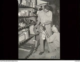 NEW GUINEA. C. 1943. FLIGHT LIEUTENANT L. L. BRAUND OF WILLIAMSTOWN, VIC (RIGHT), INSPECTING AN AERO ENGINE CYLINDER HELD BY CORPORAL J. SHAWCROFT OF HAMPTON, VIC, AT A RAAF EQUIPMENT STORE