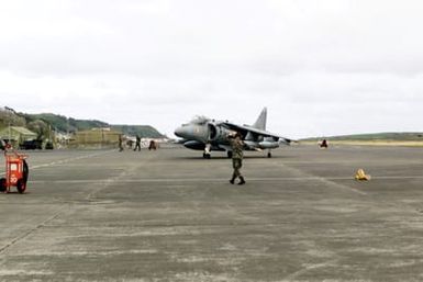 Rear view long shot as US Air Force Technical Sergeant Jeff McCoy of the 65th Operational Support Squadron marshall's an AV-8B Harrier of Marine squadron VMA 223 from Ewa Oahu, Hawaii at Lajes Field, Azores, Portugal. The marines were transitioning Lajes enroute to Greece
