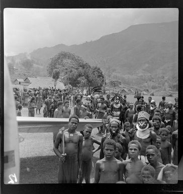 Crowd of local men, with a Qantas Empire Airways aeroplane on the airfield, Kerowagi, Simbu, Papua New Guinea