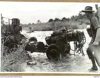 RAMU VALLEY, NEW GUINEA. 1943-11-26. A LIGHT 25 POUNDER GUN OF NO. 8 BATTERY, 2/4TH. AUSTRALIAN FIELD REGIMENT BEING HAULED ACROSS THE EVAPIA RIVER IN THE KESAWAI AREA. SHOWN ARE: VX14449 ..