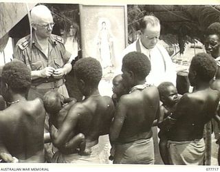 TORINKA, BOUGAINVILLE ISLAND. 1944-12-24. NX70612 CHAPLAIN H.G. REID, DEPUTY ASSISTANT CHAPLAIN GENERAL, (RC) 2ND AUSTRALIAN CORPS ASSISTED BY NX34954 CHAPLAIN F.H. GALLAGHER (IN UNIFORM) AND ..