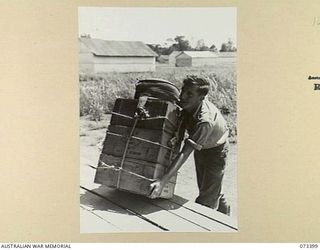 NADZAB, NEW GUINEA. 1944-05-25. VX148127 DRIVER R.C. ASLETT (1), OF THE 3RD AIR MAINTENANCE COMPANY, HANDLING RATIONS. THE RATIONS, ATTACHED TO A FOUR POINT SUPPLY PARACHUTE, WILL BE DROPPED FROM A ..