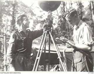 BOUGAINVILLE ISLAND. 1944-12-01. 419588 SERGEANT R.R. PERRY (1) RELEASING A METEOROLOGICAL BALLOON WHILE 421473 SERGEANT A. STRATTEN (2) PREPARES TO USE HIS SLIDE RULE TO MAKE THE NECESSARY WIND ..