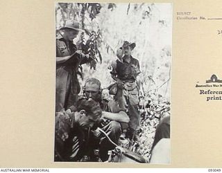 WEWAK AREA, NEW GUINEA, 1945-06-11. CAPT H.A. COULSTON, OFFICER COMMANDING B COMPANY, 2/8 INFANTRY BATTALION (1) ON THE TELEPHONE WITH SIG J.P. CASSIDY (2) BESIDE HIM DURING UNIT ACTIVITY IN THE ..