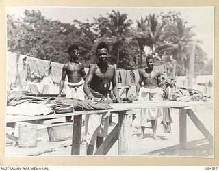 LABU, NEW GUINEA. 1944-12-18. A NUMBER OF NATIVE BOYS EMPLOYED AT 55 PORT CRAFT COMPANY. THE BOYS WHO WORK AT A NUMBER OF CHORES, ARE AT THE WASH BENCHES WASHING MEN'S CLOTHES