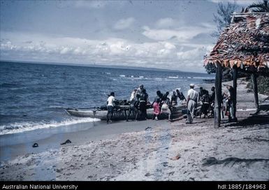 Men pushing canoe out to sea