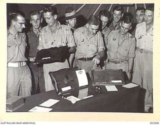 LAE AREA, NEW GUINEA. 1945-06-03. SERGEANT H.J. HOKIN, WOODWORK INSTRUCTOR AT 112 CONVALESCENT DEPOT (2), EXPLAINING THE FINER POINTS OF PRIZE WINNING TEA TRAYS TO A GROUP OF INTERESTED SPECTATORS. ..