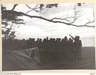 DAGUA, NEW GUINEA. 1945-03-30. MEN OF 2/2 INFANTRY BATTALION ATTENDING A GOOD FRIDAY SERVICE BEING CONDUCTED ON THE BEACH BY CHAPLAIN I.W. ALCORN, LATE IN THE EVENING. IN THE FOREGROUND IS A ..