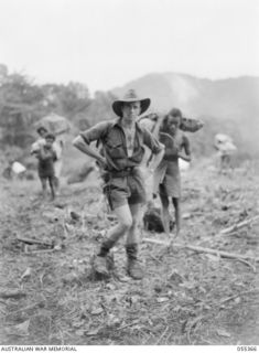 Goodview, New Guinea, 3 August 1943. SX7174 Captain Ivor H. T. Hele, Official War Artist, Military History Section, at the Goodview supply dropping ground, accompanied by native bearers