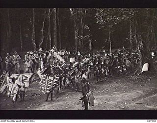 DOBODURA, NEW GUINEA. 1943-10-10. NATIVE CEREMONIAL DANCES IN PROGRESS IN THE VILLAGE CLEARING WERE ATTENDED BY ALLIED TROOPS AND NURSES