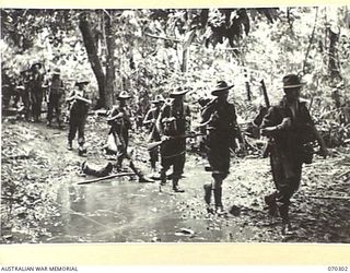 WEBER POINT, MALALAMAI, NEW GUINEA, 1944-02-09. MEMBERS OF "B" COMPANY, 30TH INFANTRY BATTALION, CROSSING A SHALLOW CREEK BETWEEN WEBER POINT AND MALALAMAI. THEY HAVE BEEN ADVANCING FROM ROINJI (2) ..