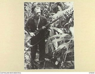 BOUGAINVILLE ISLAND. 1945-01-21. QX35897 CORPORAL P.E. HOGAN, A MEMBER OF A CONTACT PATROL FROM "D" COMPANY, 42ND INFANTRY BATTALION TAKING COVER DURING A PATROL THROUGH THE SWAMP AREA