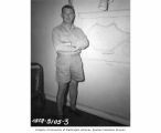 CAPT Thomas Henry Hederman, USN, standing by a map of Bikini Atoll in his stateroom aboard the USS CHILTON, summer 1947