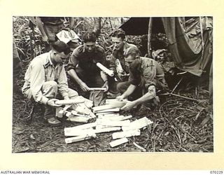 FARIA VALLEY, NEW GUINEA. 1944-02-10. 58/59TH INFANTRY BATTALION MEMBERS SORTING NEWSPAPER MAIL AT MAIN STREAM, IRIE, IN THE UPPER REACHES OF THE FARIA RIVER. IDENTIFIED PERSONNEL ARE: VX91591 ..