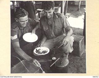 KARAWOP, NEW GUINEA, 1945-09-18. STAFF-SERGEANT A.R. ANDERSTON (1) AND TROOPER H. HINDLE (2), MEMBERS OF 2/6 CAVALRY COMMANDO REGIMENT EDUCATION SECTION, HELPING THEMSELVES TO FOOD