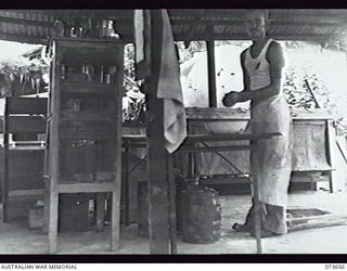 SALAMAUA, NEW GUINEA. 1944-06-01. QX18560 PRIVATE R. E. PIETZMAN, THE PLATOON COOK AT THE 2ND MARINE FOOD SUPPLY PLATOON, AT WORK IN THE UNIT COOKHOUSE