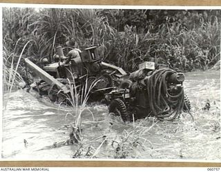 RAMU VALLEY, NEW GUINEA. 1943-11-26. A LIGHT 25 POUNDER GUN OF NO. 8 BATTERY, 2/4TH AUSTRALIAN FIELD REGIMENT BEING HAULED ACROSS THE EVAPIA RIVER IN THE KESAWAI AREA